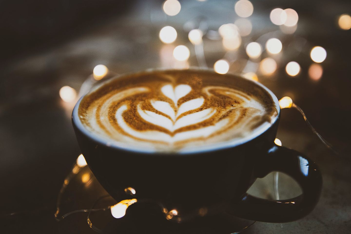 Taza de café con arte latte y luces cálidas bokeh de fondo